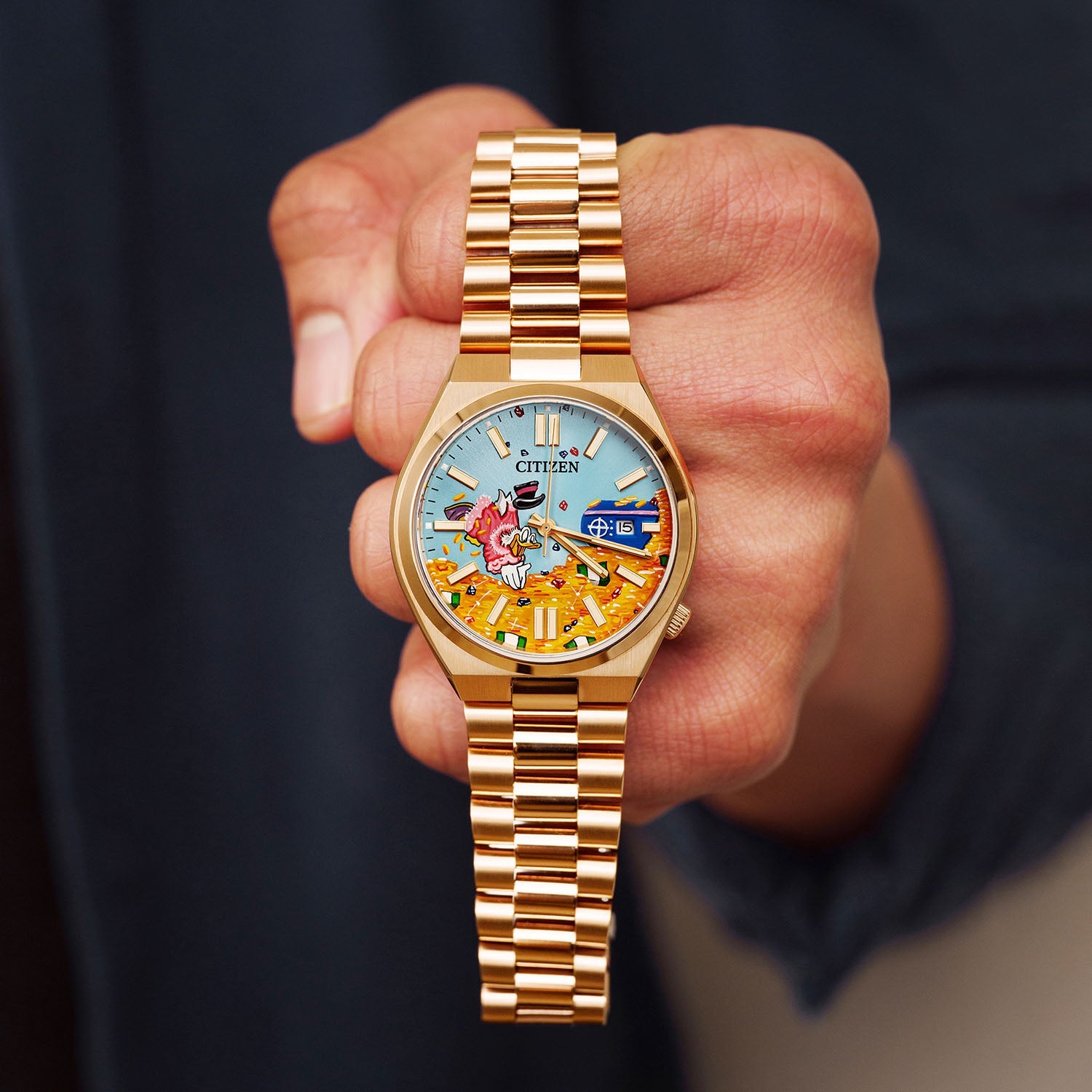 Citizen Tsuyosa Dive in Time held in hand — full view of the hand-painted dial with a character plunging headfirst into gold beneath a clear blue sky, 40mm rose gold-plated automatic, a bespoke timepiece by IFL Watches.