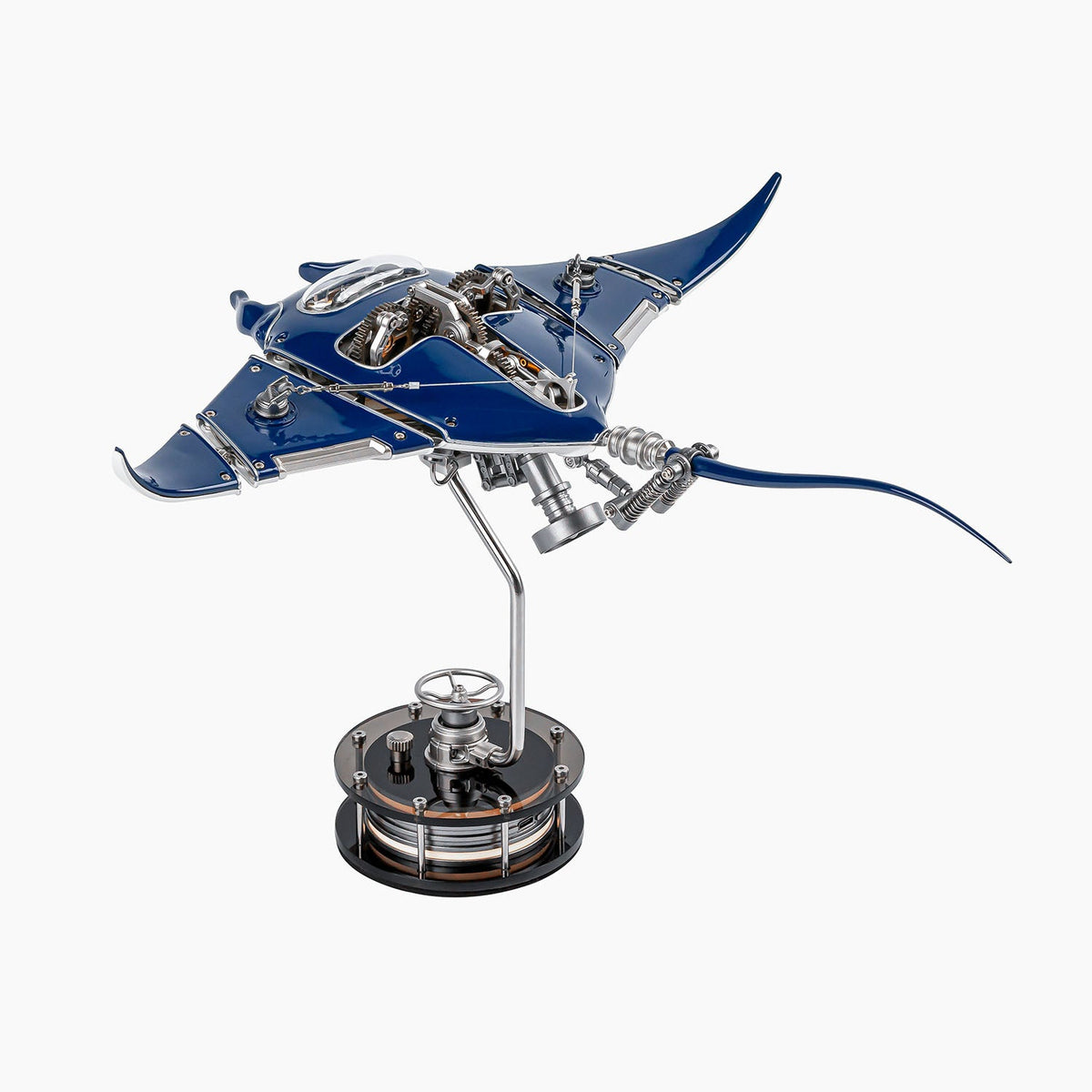 Mecha Ray Blue — motorised manta seen from the side, wings lowered and the gear train exposed along its back, mounted on a dark drive base, kinetic metal sculpture by IFL Watches.