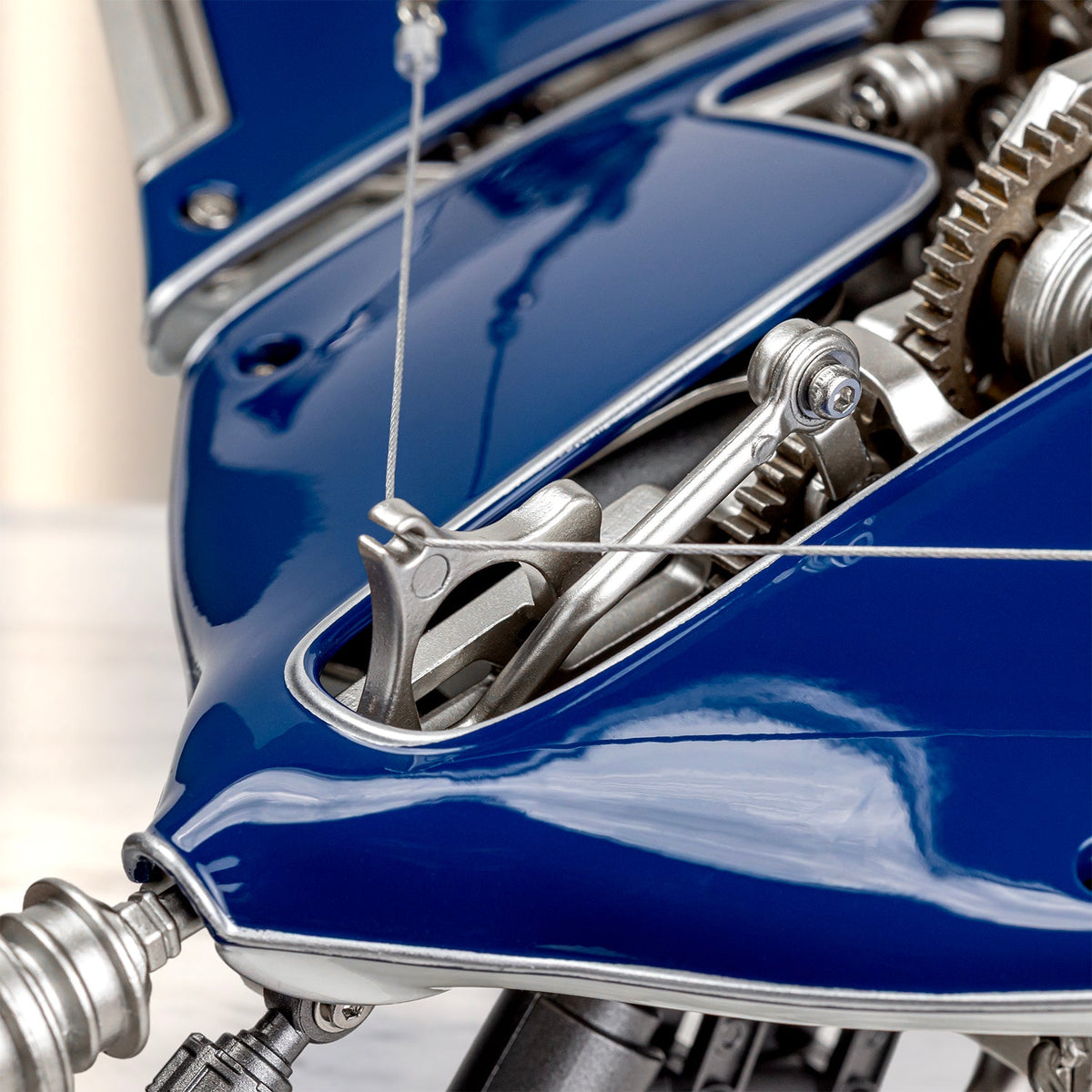 Mecha Ray Blue — close view of a tensioned steel cable running to the wing mechanism above the lacquered body, motorised metal sculpture by IFL Watches.