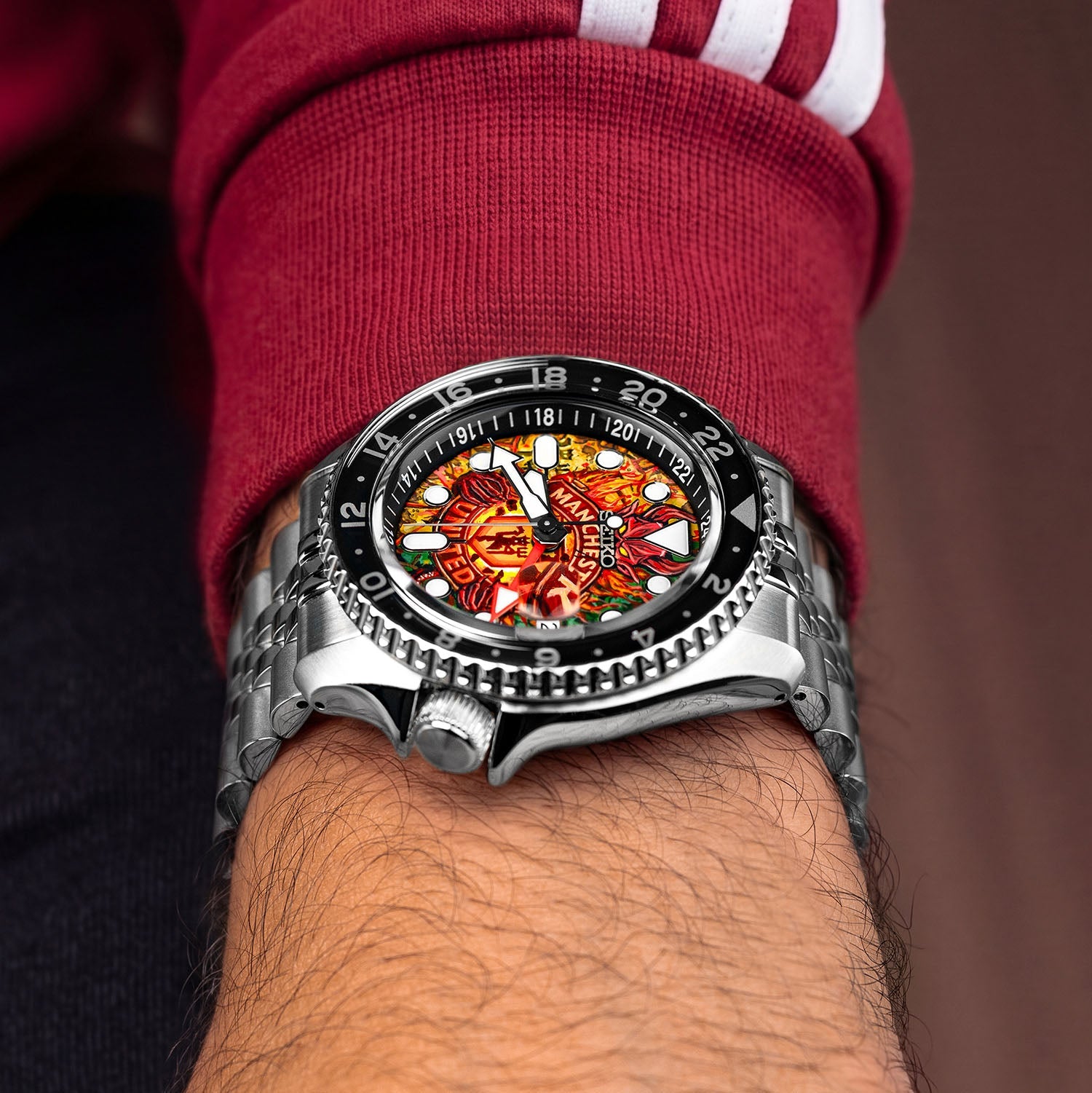 The Red Devils Concept on wrist — crown-side view showing the 42.5mm case profile, black GMT bezel, and jubilee-style bracelet with the hand-painted fiery crest dial, a bespoke timepiece by IFL Watches.