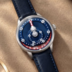 Mandetbrote Orbital Blue Kiss — Resting on beige suede, showing the red-and-white hour disc, available at IFL Watches.