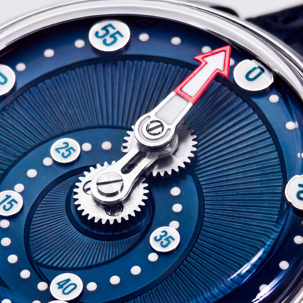 Mandetbrote Orbital Blue Kiss — Macro detail of the geared minute arm and red-tipped hand over the radiating dial texture, available at IFL Watches.