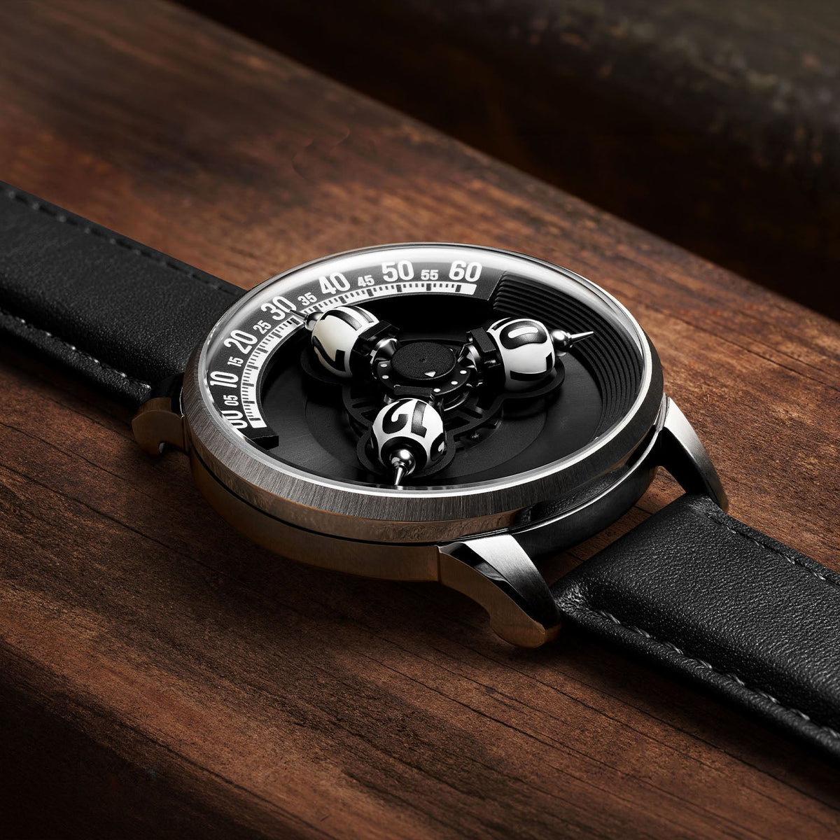 Vortichron Timeorb Midnight Black — Low side view on wood, showing the case profile and raised spheres under sapphire crystal, available at IFL Watches.