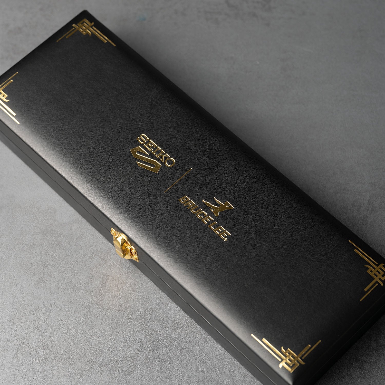 Commemorative box for Seiko 5 Sports 55th Anniversary Bruce Lee Limited Edition watch, featuring gold embossed logos of Seiko and Bruce Lee, with elegant black design and gold accents.